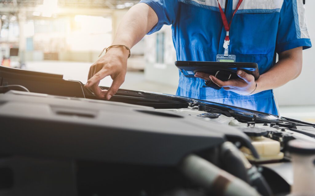 Auto mechanic are checking the condition of the car according to the month. The technician uses the tablet to check.