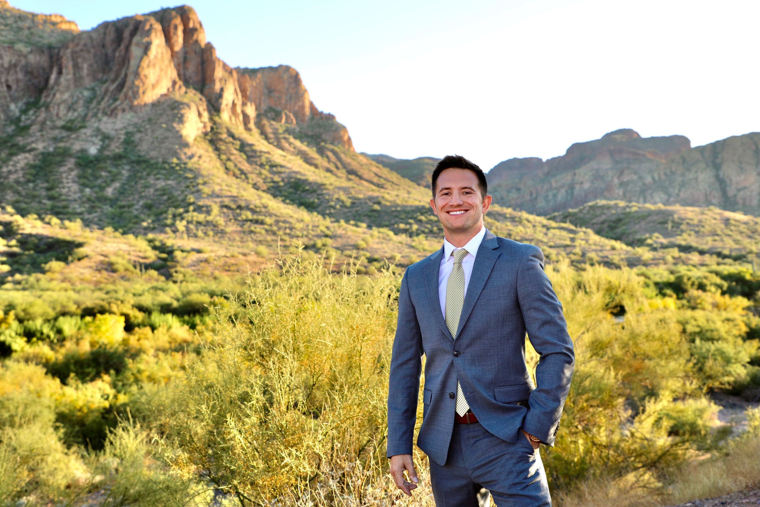 Man standing outside in the desert with a suit and tie on posing for the camera